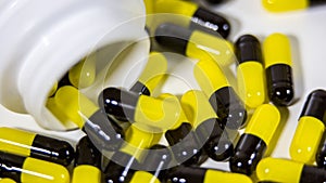 Close up on a bottle of prescription drugs falling out. Black and yellow pills