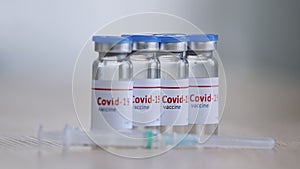 Close-up bottles with vaccine drug against covid19 virus remedy of coronavirus immunization stand on wooden table near