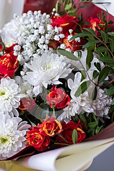 Close up bouquet of pink roses, white chrysanthemums, gypsophila and sprigs of greenery