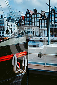 Close-up of the bow front of the wooden ship and anchor. Amsterdam Netherlands dancing houses over river Amstel in the