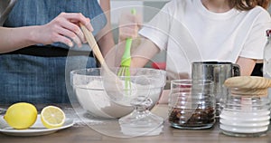 Close-up of bowl with dough, childrens hands interfering with spoon of flour