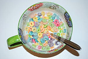 Close up of a bowl full of fruit flavored loops of sugar ready to eat breakfast cereal with a spoon sticking out
