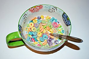 Close up of a bowl full of fruit flavored loops of sugar ready to eat breakfast cereal with a spoon sticking out