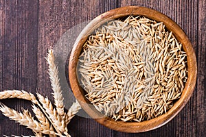 Close-up of a bowl with oat seeds and ears of oats on the table. Organic harvest