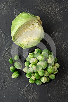 Close-up bowl with raw brussels sprouts and cabbage on concrete background. Vegetarian food. Selective focus. Top view