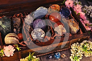 Close up of box with magic crystals and stones, sakura spring flowers on planks