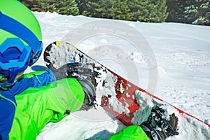 Close-up of the boy attaching snowboard sitting in snow