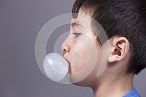 Close up of boy blowing bubble.