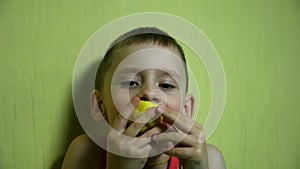 A close-up boy, a Caucasian child of preschool age eats lemon with anticipation, then makes a grimace