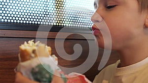 close-up of a boy eating a big burger. hungry child eats a burger with appetite
