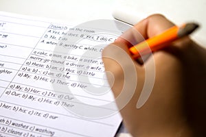 Close-up of boy hand with pencil writing English words. The boy writes his first test on English. Child writing