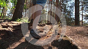 close up of boy legs goes uphill, boy walks in summer, the glare of the sun, hike through the forest