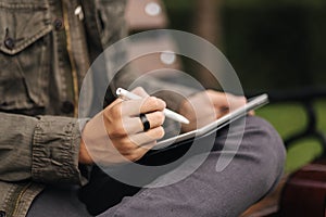 Close-up of boy painting in tablet using pencil. Young designer using tablet outdoor. Autumn time