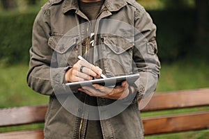 Close-up of boy painting in tablet using pencil. Young designer using tablet outdoor. Middle selection. Autumn time