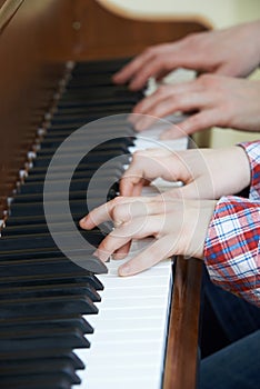 Close Up Of Boy Playing Piano Duet With Teacher