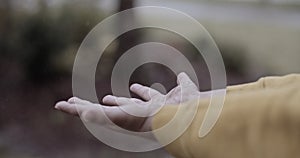 Close up of a boy playing in the rain and getting his hands wet outside his home on a rainy and cloudy day