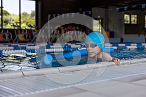 Close up boy swimmer o school boy learning how to swim in a pool wearing in swimming cap and goggles