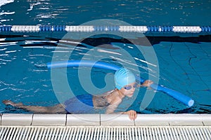 Close up boy swimmer o school boy learning how to swim in a pool wearing in swimming cap and goggles