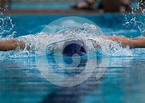 Close up of Boy swimming butterfly stroke with face in water spray and water bubble and sun highlights