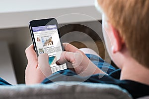 Boy Using Social Networking Site On Mobile Phone