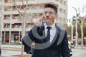 Close up of boy walking with blue suit and calling by phone in city