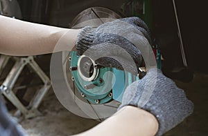 Close up brake calliper of car and a man use L wrench remove bolt of pad brake in maintenance car concept