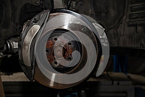 A close-up on the brake  of a car with pads, discs, a caliper on a lift in a vehicle repair workshop. Auto service industry