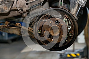 A close-up on the  brake system of a car with hub on a lift in a vehicle repair workshop. Auto service industry