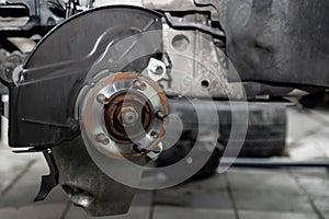 A close-up on the brake system of a car with hub on a lift in a vehicle repair workshop. Auto service industry