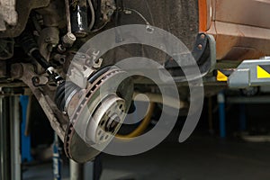 A close-up on  brake system of a car with pads, discs, a caliper on a lift in a vehicle repair workshop. Auto service industry