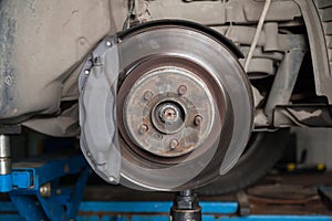 A close-up on  brake system of a car with pads, discs, a caliper on a lift in a vehicle repair workshop. Auto service industry