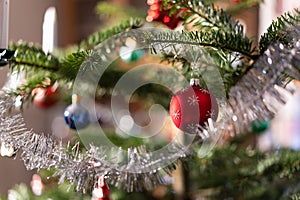 Close-up of a branch of Christmas tree with wreath and red baubles at daytime