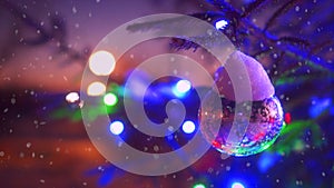 Close-up branches of Christmas tree with colorful blinking lights bokeh surrounded by falling snow