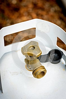 Close up of the brass knob on the top of a propane tank in a family backyard