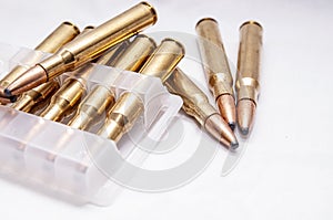 A close up of brass rifle bullets used for hunting, some in a plastic case