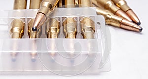 A close up of brass rifle bullets used for hunting, some in a plastic case