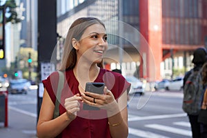 Close-up of Brazilian business woman hail a vehicle using mobile app looking to the side on Paulista Avenue, Sao Paulo, Brazil photo