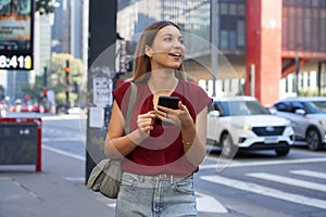 Close-up of Brazilian business woman hail a vehicle using mobile app looking to the side on Paulista Avenue, Sao Paulo, Brazil photo