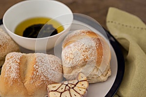 Close up of bread by olive oil in bowl on plate