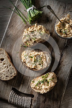 Close-up of bread slice with traditional Slovak bryndza spread made of sheep cheese with freshly cut chives placed on rustic wood