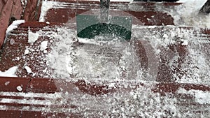 Close-up breaking ice and snow with hand ice chopper. Cleaning paving slabs from outdoor steps with icebreaker tool in