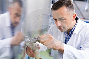 Close-up brewer filling beer in bottle from tank