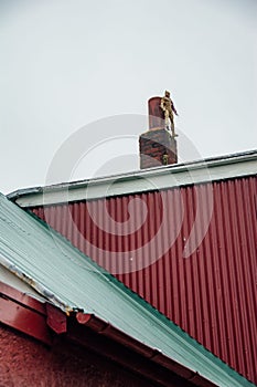 Close-up of a brick chimney poking out of the roof of a house against a backdrop of cloudy sky