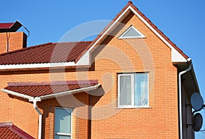 Close up on brick house with asphalt shingles roof and rain gutters in problem area.