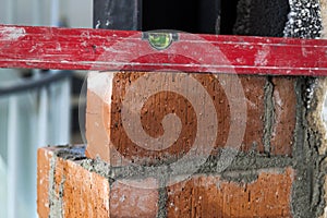 Close up of bricklaying industrial installing bricks on construction site wall with working tools, mortar, level