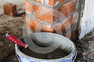 Close up of bricklaying industrial installing bricks on construction site wall with working tools, mortar, level