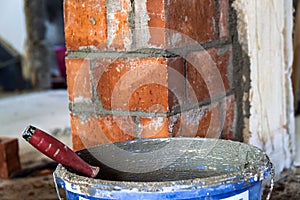 Close up of bricklaying industrial installing bricks on construction site wall with working tools, mortar, level