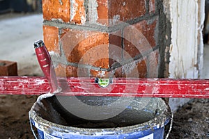 Close up of bricklaying industrial installing bricks on construction site wall with working tools, mortar, level