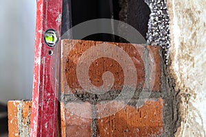 Close up of bricklaying industrial installing bricks on construction site wall with working tools, mortar, level