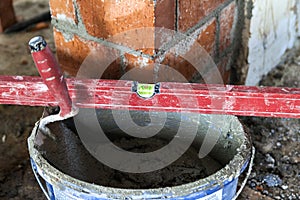 Close up of bricklaying industrial installing bricks on construction site wall with working tools, mortar, level